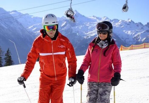 Skilehrer mit Skischülerin am Berg